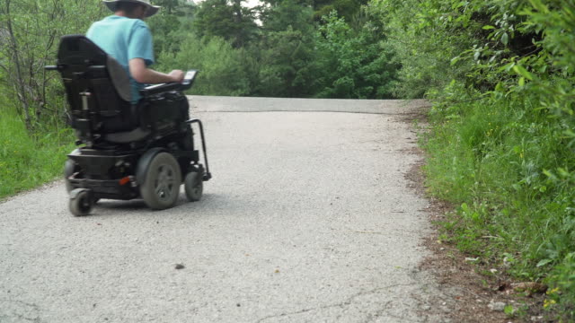 Vídeo-de-resolución-4k-de-un-hombre-en-silla-de-ruedas-eléctrica-conduciendo-fuera-de-la-carretera-en-la-naturaleza