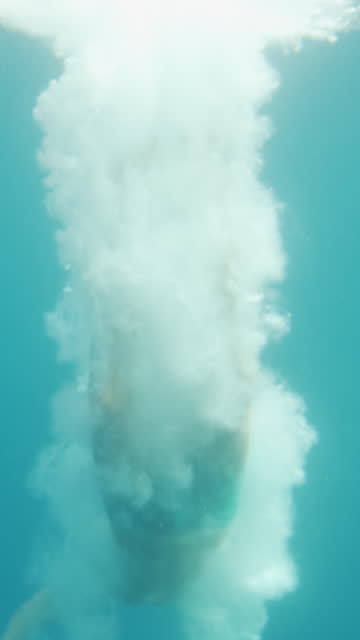 Unterwasser-Aufnahmen-von-Mann-springen-in-Wasser-und-Schwimmen.-Tauchen-im-Ozean.-Videomaterial-mit-vertikaler-Bildschirmausrichtung-9:16