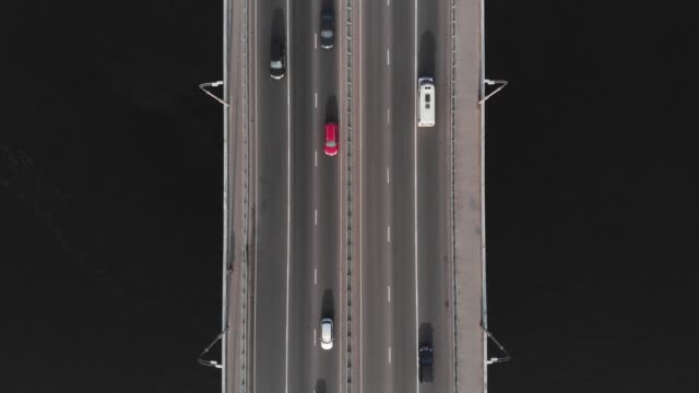 Bridge-highway-dark-water-red-yellow-cars-in-traffic-aerial-top-view
