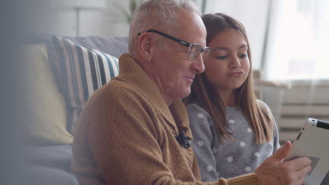 Großvater-und-Enkelin-mit-Tablet-und-Lachen
