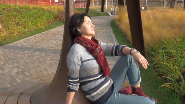 Kaukasische-Frau-sitzt-auf-einer-Parkbank-geschlossen-ihre-Augen