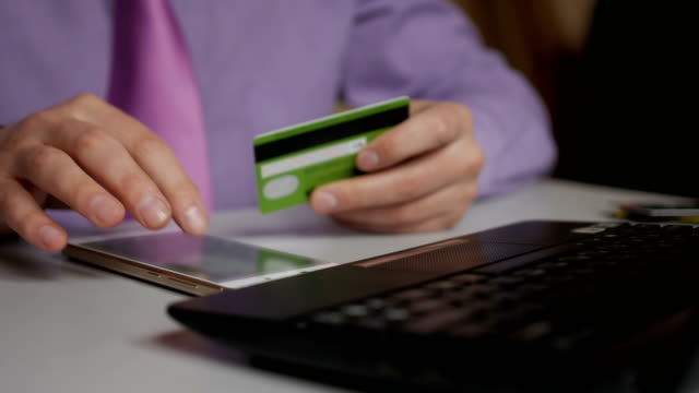 A-businessman-in-a-purple-shirt-and-tie-is-making-a-payment-to-internet-banking.-Shopping-online-with-credit-card-on-smartphone.