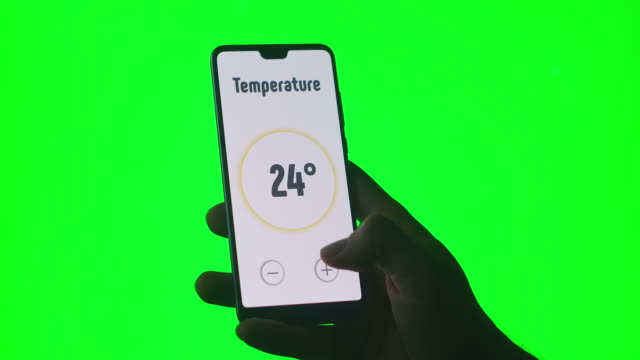 Die-Hand-steuert-die-Smart-Home-App-mit-einem-Smartphone-auf-grünem-Chromakey-Hintergrund