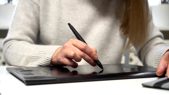Diseñadora-femenina-usando-tableta-gráfica-en-casa.