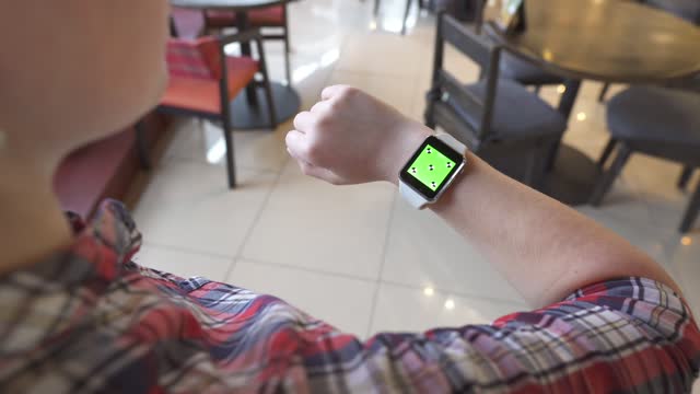 Smart-Uhr-mit-grünem-Bildschirm.-Person-verwendet-elektronisches-Gerät-auf-der-Hand.-Neue-Technologien