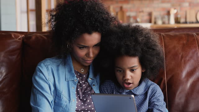Afrikanische-Mutter-erziehen-kleine-Tochter-hält-Tablet-über-Internet-Website