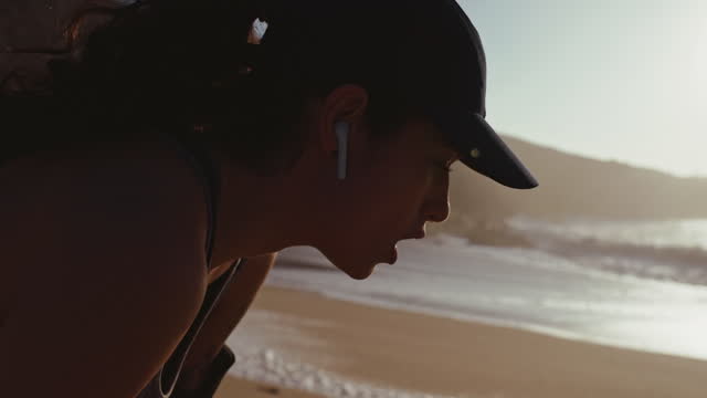 Mujer-con-auriculares-descansando-después-de-correr-en-la-playa
