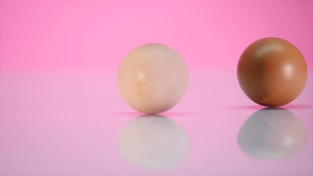 Two-eggs-are-spinning-on-a-table-on-a-pink-background