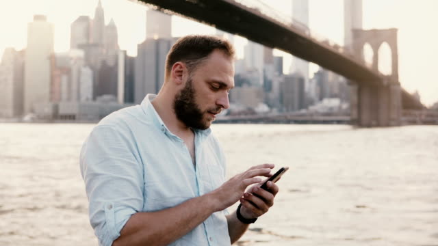 Ernste-Europäische-Geschäftsmann-Eingabe-Nachricht-auf-Smartphone-Messenger-app-in-New-York-City-Sonnenuntergang-Landschaft-4K