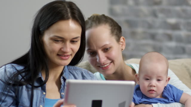 Weibliches-Paar-mit-Baby-Blick-auf-Tablet