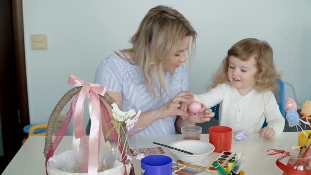 Madre-y-su-pequeña-hija-pintando-huevos-de-Pascua