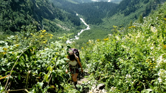 Kletterer-Frau-Tourist-mit-einem-Rucksack-steigt-bergauf-im-Hintergrund-von-einer-wunderschönen-Landschaft.-Das-Mädchen-klettert-im-Sommer-zu-Fuß