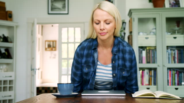 Attraktive-blonde-Frau-sitzt-am-Tisch-mit-Laptop