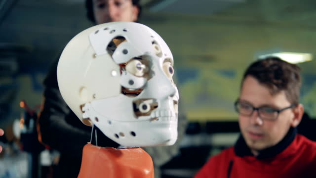 Detailansicht-des-Roboters-Gesichts-mit-Spezialisten-reden-im-Hintergrund