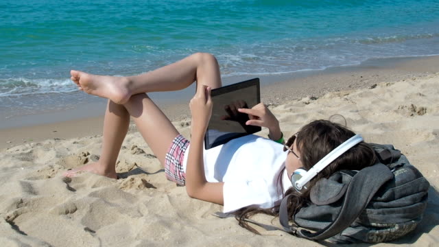 Child-listening-music-on-beach.-Using-tablet.