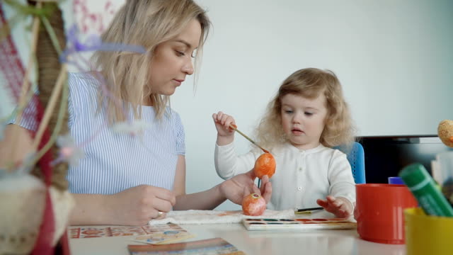 Mother-and-her-little-daughter-painting-Easter-eggs