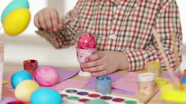 Niño-feliz-vistiendo-orejas-de-conejo-pintando-huevos-el-día-de-Pascua.
