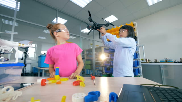 Zwei-Schulkinder-fixieren-Drohnenmodell-in-moderner-Technik-Schulklasse-4K.