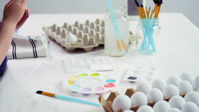 Niña-pequeña-pintando-huevos-de-Pascua-con-pintura-acrílica.