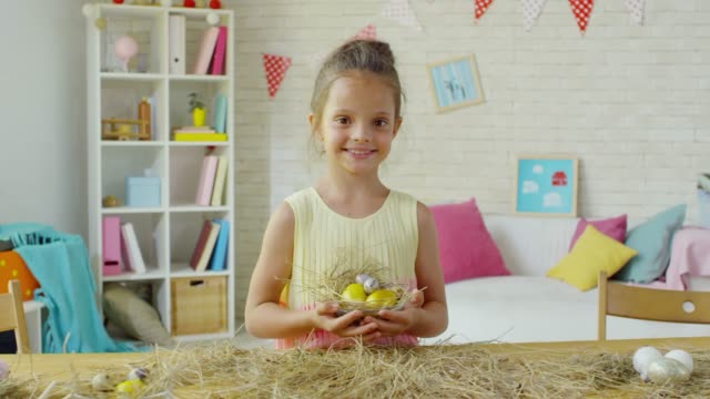 Feliz-niña-posando-con-huevos-de-Pascua-en-hay-Nest