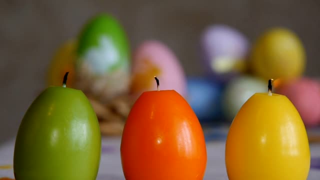 Velas-hechas-en-forma-de-huevo-de-Pascua.-Las-velas-se-extinguió-desde-el-aire..-Verde,-naranja,-amarillo.-Huevos-de-Pascua-velas-y-coloridos-huevos-de-Pascua-en-el-fondo.