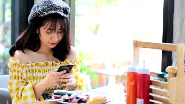 Asian-young-woman-taking-a-photo-of-breakfast-with-smartphone-social-media