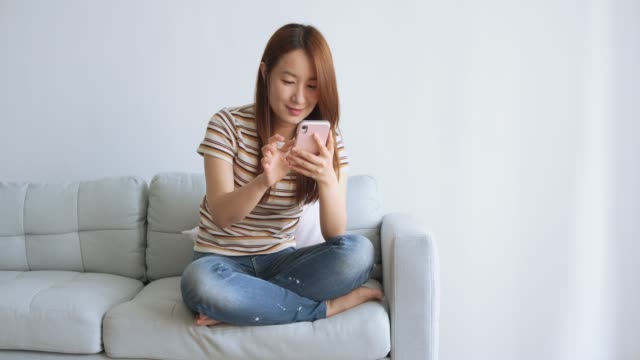 Asian-woman-using-cellphone-in-living-room