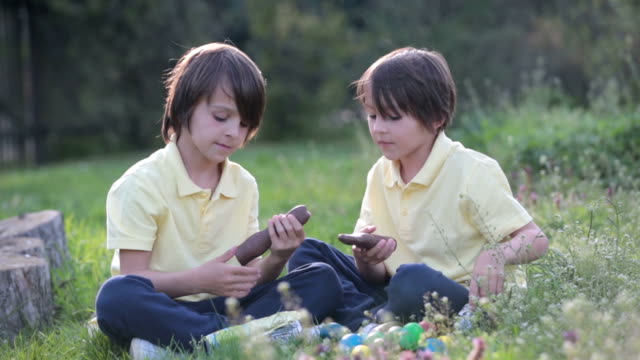 Sweet-children,-boy-brothers-with-bunny-ears,-egg-hunting-for-Easter,-child-and-Easter-day-traditions.-Kids-and-holidays