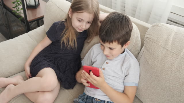 Children-with-mobile-phone-on-sofa