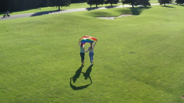 Drone-view-of-gay-couple-running-holding-lgbt-flag