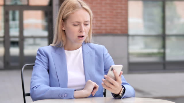 Young-Businesswoman-Upset-by-Loss-while-Using-Smartphone
