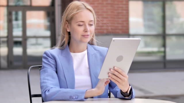 Joven-empresaria-sentada-al-aire-libre-y-usando-la-tableta