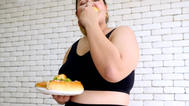 Mujer-joven-con-sobrepeso-en-ropa-deportiva-disfrutar-de-comer-comida-rápida-después-del-ejercicio