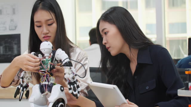 Asiatische-Frau-Ingenieur-Montage-und-Testen-von-Robotik-Antworten-im-Labor.-Architekten-Design-Circuit-Meeting-teilen-Technologieideen-und-kooperierende-Entwicklungsroboter.