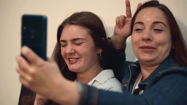 Two-young-girls-having-fun,-laugh-and-make-selfie