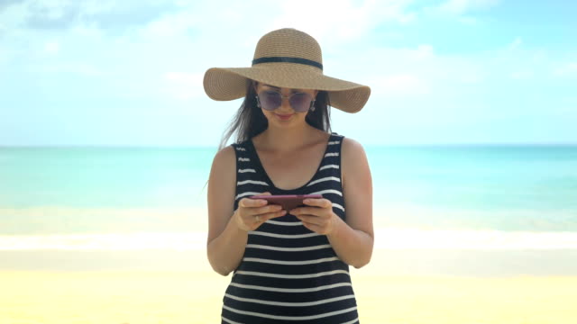 traveler-woman-using-phone-app-on-beach-at-summer-vacation.