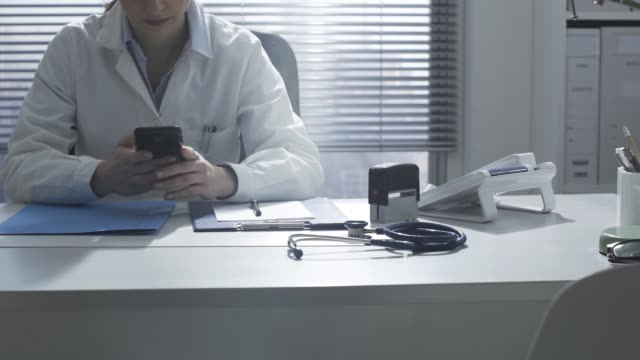Arzt-arbeitet-im-Büro-und-benutzt-ein-Smartphone