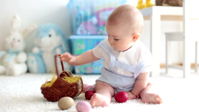 Süßes-Kleinkind-Kind,-Baby-Junge,-im-sonnigen-Wohnzimmer-spielen-mit-Ostern-Schokolade-Hase-und-bunte-Ostereier