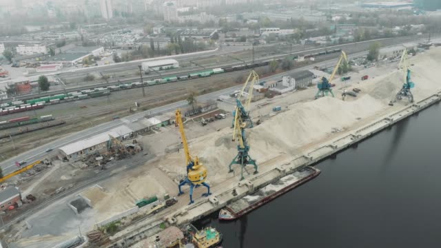 Sand-Iron-industrial-barge-with-sand-floating-near-cargo-working-cranes.-Extraction-of-river-sand-in-docks