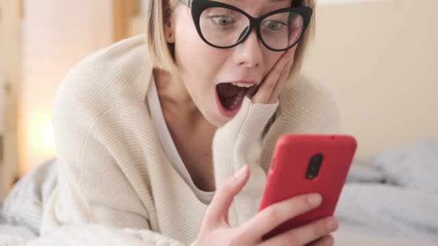 Mujer-sorprendida-usando-el-teléfono-móvil-en-la-cama