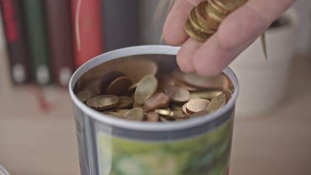 Male-hand-pours-euro-coins-into-a-jar