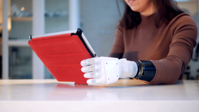 Woman-holds-a-tablet-with-robotic-hand,-close-up.