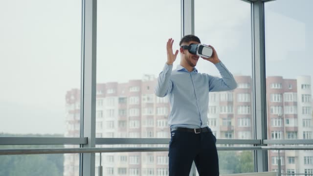 Close-up-Young-man-sitting-at-a-desk-in-the-office-uses-augmented-reality-glasses-to-work-on-business-projects-in-various-fields.-Work-in-Virtual-Reality
