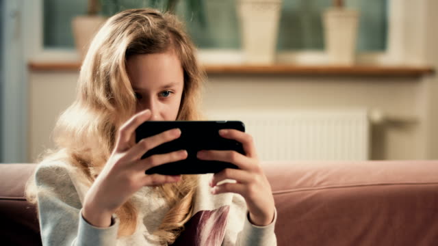 Chica-rubia-joven-centrarse-en-la-pantalla-del-teléfono-inteligente.-Nueva-aplicación-de-juego-móvil