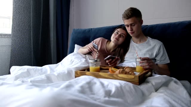Cute-couple-surfing-net-with-smartphones-in-bed
