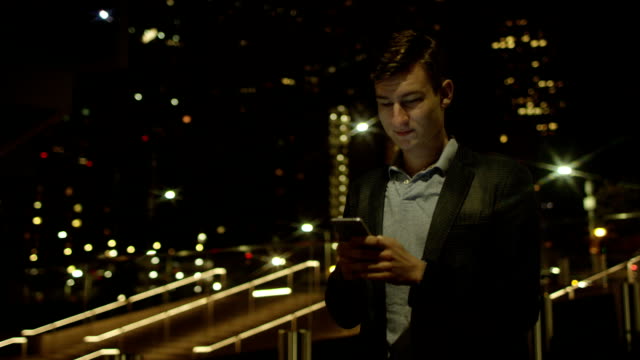 Hübscher-junger-Geschäftsmann-nutzt-sein-Smartphone-für-die-Kommunikation-auf-einer-Straße-stehend