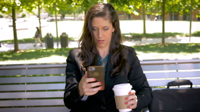 Beautiful-woman-reading-mobile-phone-app-technology-on-park-bench