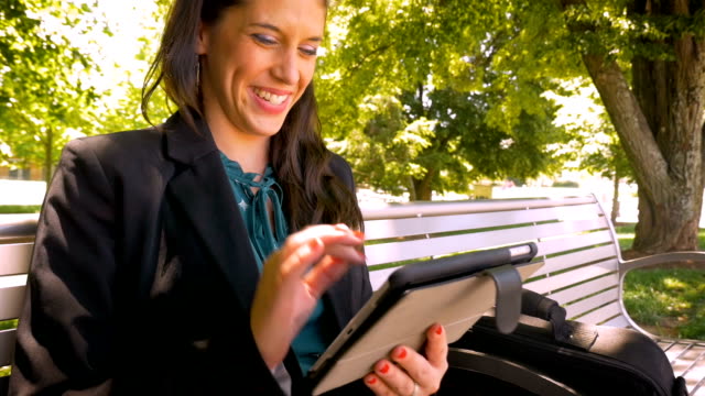 Glücklich-lächelnd-Geschäftsfrau-arbeiten-an-digitalen-Tablet-Technologie-im-park