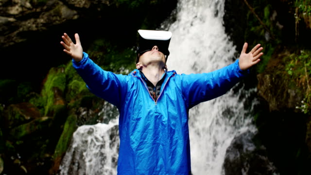Ein-Mann-nutzt-virtual-Reality-Brille-auf-dem-Hintergrund-von-einem-Wasserfall-Berg