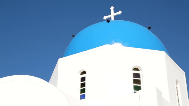 Amazing-blue-dome-church-on-Santorini,-tourists-go-sightseeing-on-Greek-island